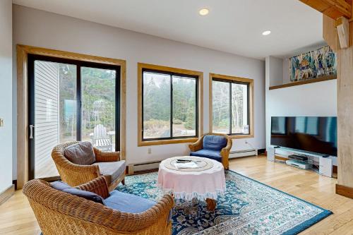 a living room with chairs and a table and a tv at Oceanfront Gem in East Boothbay
