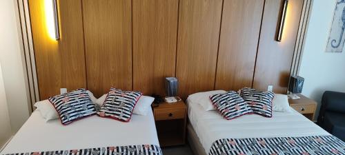 two beds in a room with wood paneling at Búzios Beach Resort Residencial 1322 in Búzios