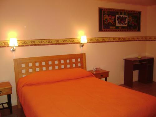 a bedroom with an orange bed and two night stands at Ayelen Apart Hotel in Calama