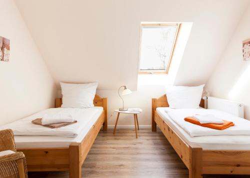 duas camas em um pequeno quarto com janela em Toplage direkt an der Steilküste - FeWo 2 "Ostseenest" Hohwacht em Hohwacht