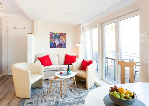 uma sala de estar com um sofá branco e almofadas vermelhas em Toplage direkt an der Steilküste - FeWo 2 "Ostseenest" Hohwacht em Hohwacht