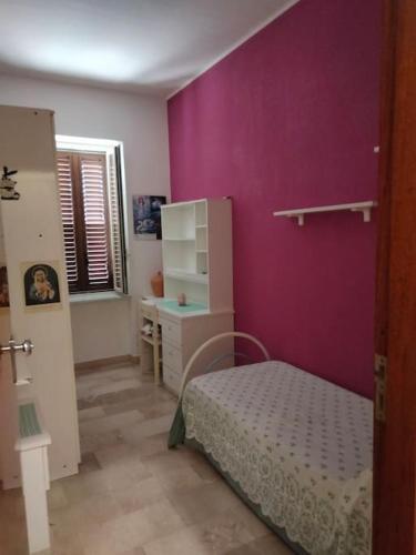 a bedroom with purple walls and a bed and a desk at Appartamento Ficarra Via Logge 16 in Ficarra