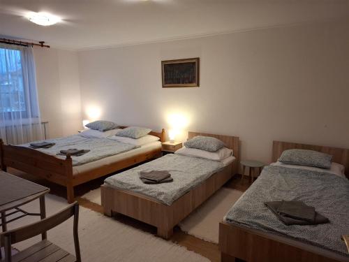 a room with two beds and a table and a table at Emma vendégház in Sárospatak