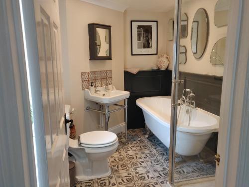 a bathroom with a tub and a toilet and a sink at The Stable, Cuffern Manor Cottages in Haverfordwest