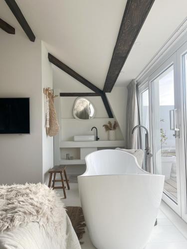 a white bath tub in a bedroom with a window at Het sfeerhuis aan zee in Vlissingen