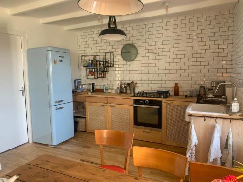 eine Küche mit einem Kühlschrank sowie einem Tisch und Stühlen in der Unterkunft Maison cosy in Larmor-Baden