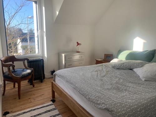 une chambre avec un lit, une chaise et une fenêtre dans l'établissement Maison cosy, à Larmor-Baden