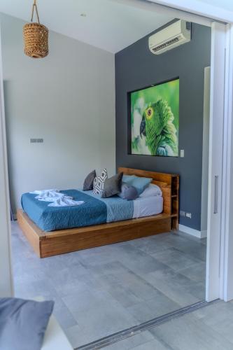 a bedroom with a bed with a picture of a bird on the wall at Lilan Nature, Modern House N°2, private swimming pool in Cahuita
