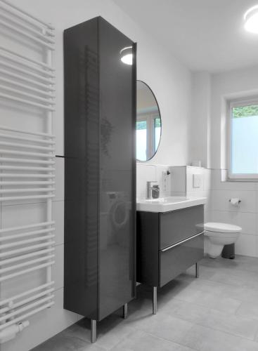 a bathroom with a sink and a toilet and a mirror at INIKAMA - Elegantes Apartment in Rosengarten