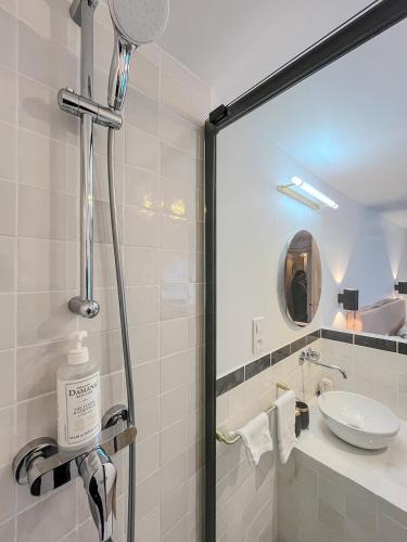 a bathroom with a shower with a sink and a mirror at Hôtel du Commerce in Cluny