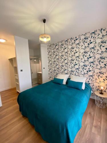 - une chambre avec un lit bleu et un mur dans l'établissement Maison familiale dans le Médoc, à Le Pian-Médoc