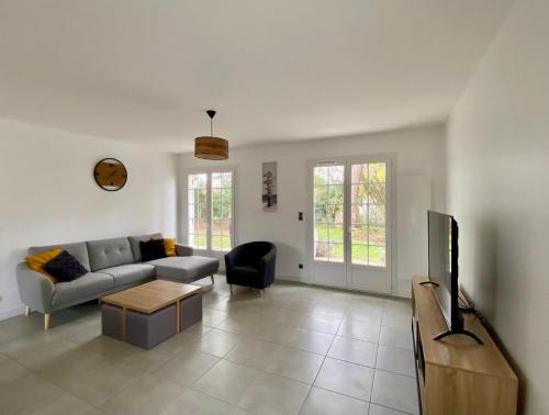 un salon avec un canapé et une télévision dans l'établissement Maison familiale dans le Médoc, à Le Pian-Médoc