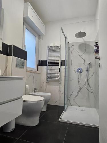 a bathroom with a toilet and a glass shower at Residenza Giardino di Roma in Vitinia