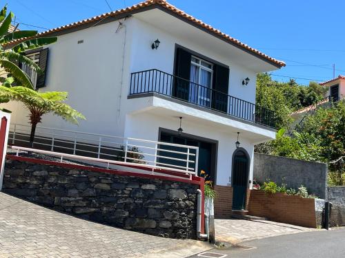 a white house with a balcony and a stone wall at Casa Nova - Maison avec garage, terrasse & Balcon in Ponta do Sol