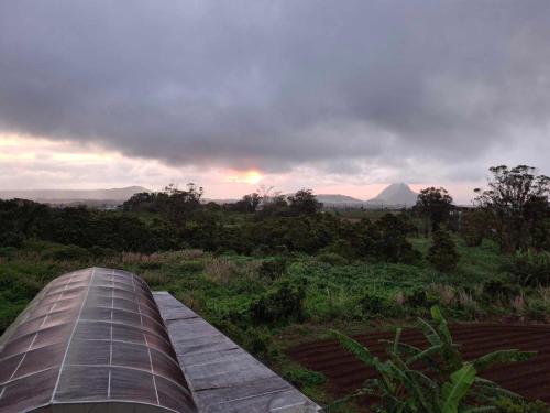 a view of the sunset from a field with a roof at Ant's residence in Curepipe