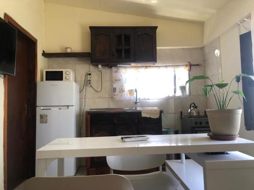 a small kitchen with a white refrigerator and a table at Casa la Popa in Barra de Valizas