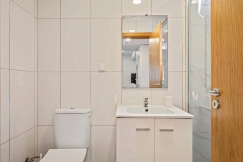 a white bathroom with a toilet and a sink at Tornos in Funchal
