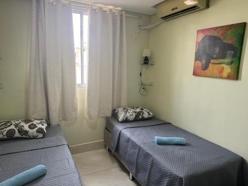 a bedroom with two twin beds and a window at Apto Aconchegante Próximo Aeroporto de VG in Várzea Grande