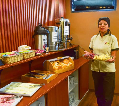 a woman standing in a kitchen holding a tray of food at Hotel Royal Qosqo in Cusco