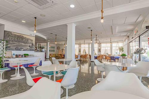 un restaurante con mesas y sillas blancas, mesas y ventanas en Hotel Altaia, en Altea