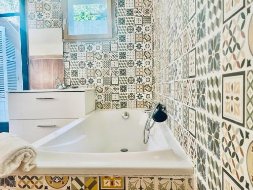 La salle de bains est pourvue d'une baignoire et d'un mur en carrelage. dans l'établissement La Maison by Simone T2, à Cannes