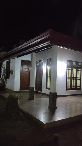 a small white house with brown doors at night at Royal Homestay cozy 2 bedroom house with all the facilities in Kalutara South