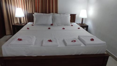 a bed with white sheets and red flowers on it at Royal Homestay cozy 2 bedroom house with all the facilities in Kalutara South