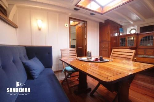 une salle à manger avec une table en bois et un canapé bleu dans l'établissement Yacht KARABOUDJAN, à Saint-Malo