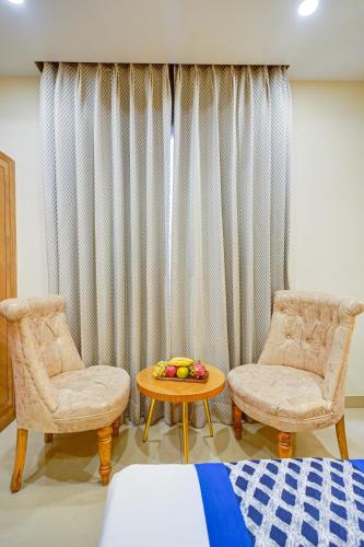 a room with a bed and two chairs and a table at Hotel Gold Palace - 03 Mins Walk From New Delhi Railway Station in New Delhi