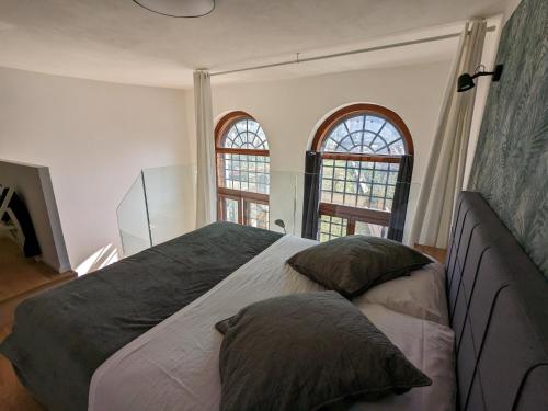 a bedroom with a large bed with two windows at mini loft Lido with own sunny & private garden in Venice-Lido