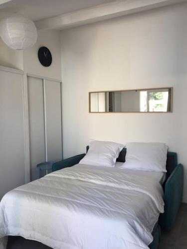 une chambre avec un grand lit blanc avec un miroir dans l'établissement Bastidon 19, à Saint-Rémy-de-Provence