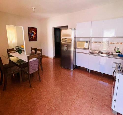 a kitchen with a table and a stainless steel refrigerator at Maravilhosa casa no centro de Foz do Iguacu in Foz do Iguaçu