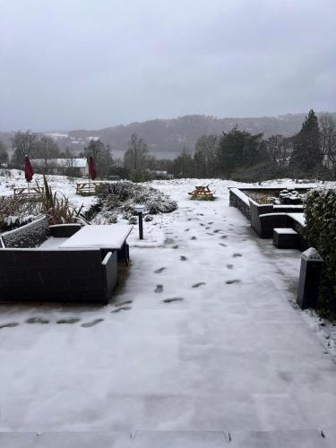 a yard covered in snow with tables and benches at The Ryebeck Hotel in Bowness-on-Windermere