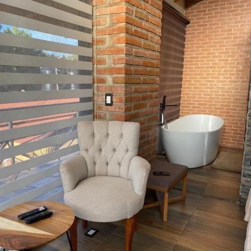 a bathroom with a chair and a bath tub at Cabaña El Atardecer, Mazamitla in Mazamitla