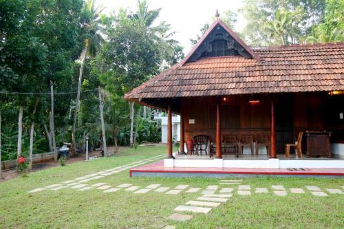 a small house with a table and chairs in a yard at Poovar Heritage Homes in Pūvār