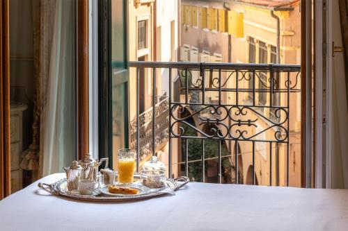 a table with a plate of food and drinks on a balcony at Majestic Toscanelli (centro storico) in Padova