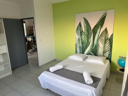 a bedroom with a bed with a painting on the wall at Maison La Surprise in Saint-Leu