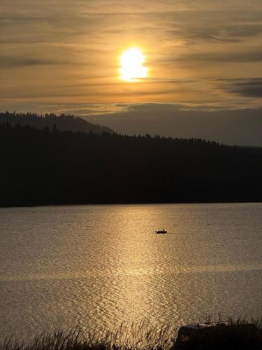 a boat on a lake with the sun in the sky at CzorsztynLakePL in Kluszkowce