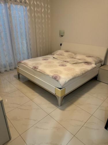 a bed in a bedroom with a white floor at Apartments Funtana with pool in Funtana
