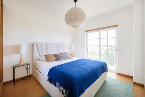 a bedroom with a bed with a blue blanket at Beach & Cascais Luxury Villa, By TimeCooler in Alcabideche