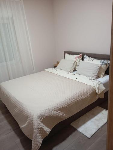 a bedroom with a bed with white sheets and pillows at Apartman KVINS in Kruševac