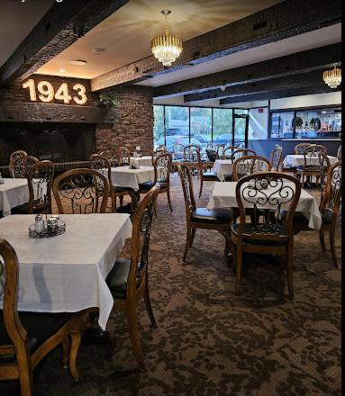 a dining room with tables and chairs and a fireplace at Pine Lake Resort and Banquets in LaPorte