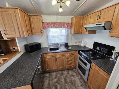 a kitchen with wooden cabinets and a stove top oven at 8 Berth Caravan - North Shore Holiday Park Skegness 3 Bedrooms in Skegness
