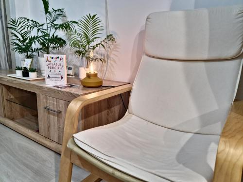 ein weißer Stuhl neben einem Tisch mit Pflanzen in der Unterkunft Apartament cu o camera Happy Color, Free Parking in Roşu