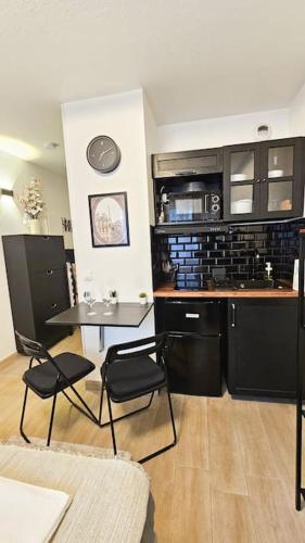 une cuisine avec des armoires noires, une table et des chaises dans l'établissement Studio 45 Arche Défense et Salle Arena Parking gratuit wifi haut débit, à Courbevoie