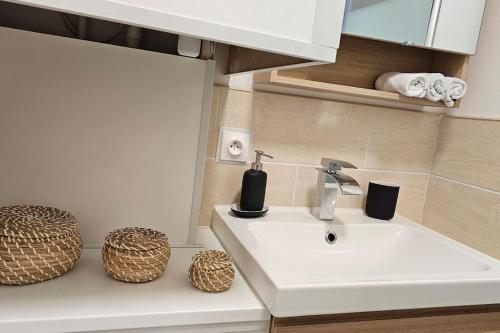La salle de bains est pourvue d'un lavabo blanc et de 2 paniers. dans l'établissement Studio 45 Arche Défense et Salle Arena Parking gratuit wifi haut débit, à Courbevoie