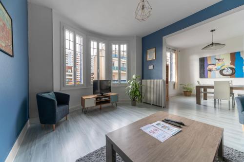 ヴィシーにあるLe Louis B - Appartement calme et lumineux proche Thermesの青い壁のリビングルーム(テーブル付)