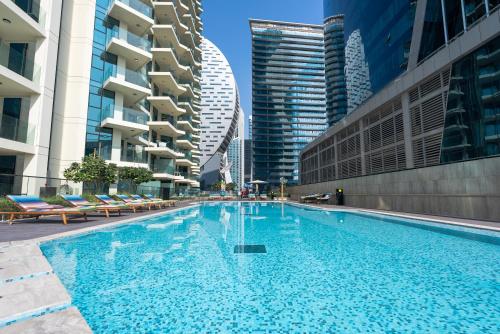 a large swimming pool in a city with tall buildings at Luxury 1 & 2 BHK Apartments, Branded & State of The Art Amenities in Dubai