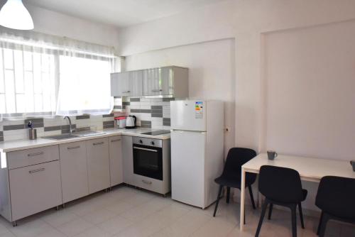 Una cocina con refrigerador y una mesa con sillas. en Roseberry Studios, en Faliraki