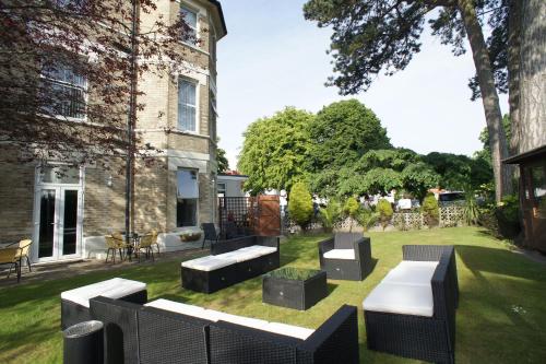 a garden with benches and tables in front of a building at Applewood Hotel in Bournemouth